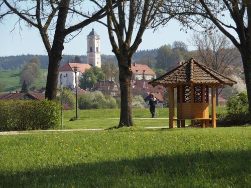a gazebo in a park with a person walking in the grass at Hotel An der Brunnader - Die Therme befindet sich 4 Geh-Minuten entfernt in Bad Birnbach