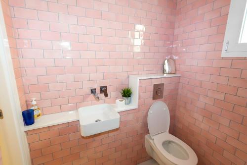 a pink tiled bathroom with a toilet and a sink at Casa de Arte in Torrox