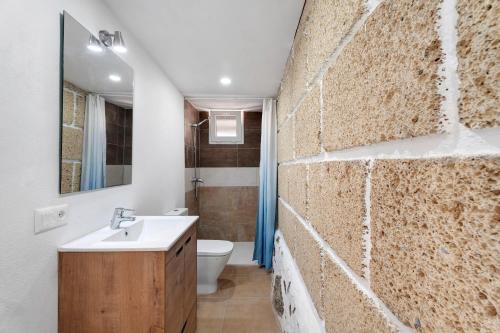 a bathroom with a stone wall with a sink and a toilet at Finca Eva in Granadilla de Abona