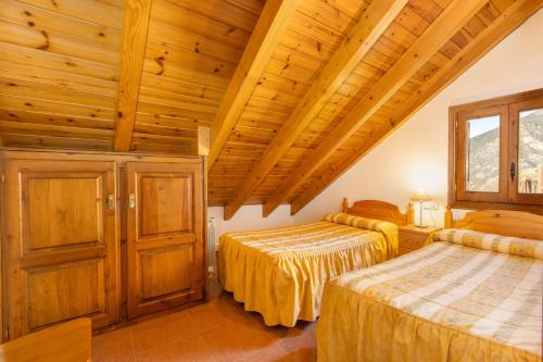 two beds in a room with wooden ceilings at La Golfa in Durro