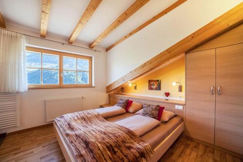 a bed in a room with a large window at Feldhof Apartment Apfeltraum in Caines