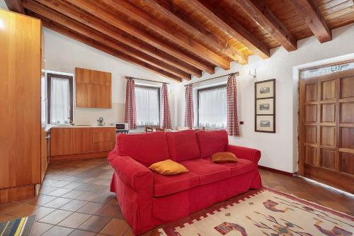 a red couch in a living room with a kitchen at Au Petit Chevrot - Classic in Aosta