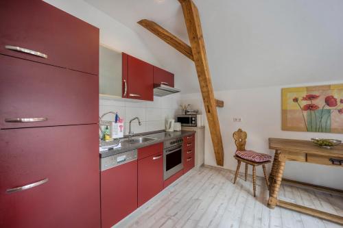 a kitchen with red cabinets and a wooden table at Ferienwohnung im Haus Kreuzthal in Buchenberg