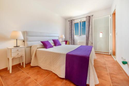 a bedroom with a large bed with purple pillows at Estrella de mar verde in Port d'Alcudia