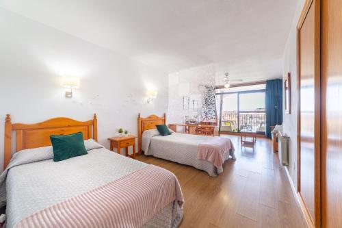 a hotel room with two beds and a window at Apartamento residencial Fénix in Roquetas de Mar