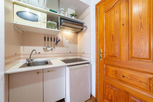 a small kitchen with a sink and a wooden door at Apartamento residencial Fénix in Roquetas de Mar