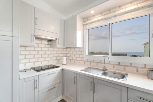 a white kitchen with a window and a sink at Loft de Tato in Frontera