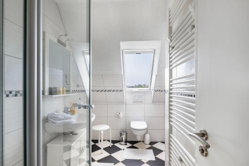 a white bathroom with a toilet and a sink at Jensenhof Pellworm in Pellworm