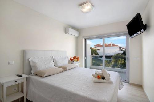 a white bedroom with a white bed and a window at Numar Residence Villa Z in Manta Rota
