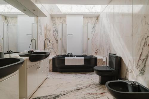 a bathroom with a black tub and two sinks and a toilet at Viana Beach Surf House in Viana do Castelo