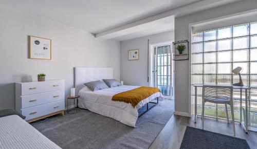 a bedroom with a bed and a table and windows at Costa Nova Ocean View in Gafanha da Encarnação