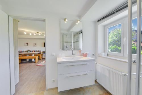 a white bathroom with a sink and a window at Fewo Trudi in Grabenstätt