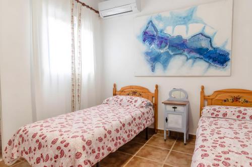 a bedroom with two beds and a painting on the wall at Casa Jema in Torrox