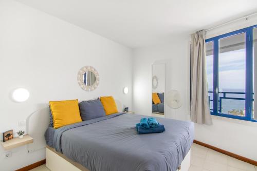 a bedroom with a bed with yellow and blue pillows at Stunning Sunset Ocean View Apt in Taurito