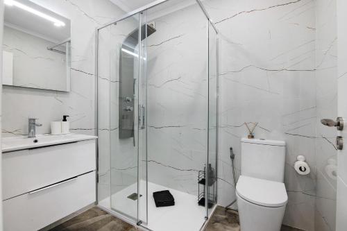 a bathroom with a toilet and a glass shower at Amazing Oura Beach Apartment in Albufeira