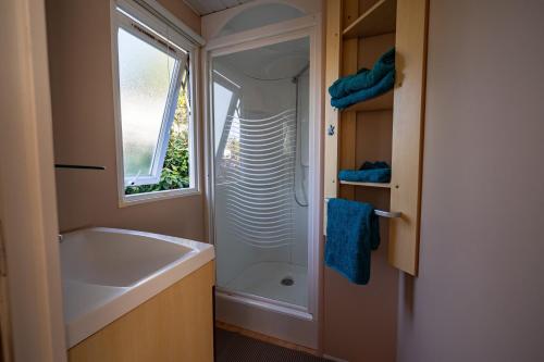a bathroom with a tub and a sink and a window at Mobilehome 4 personnes in Les Mathes