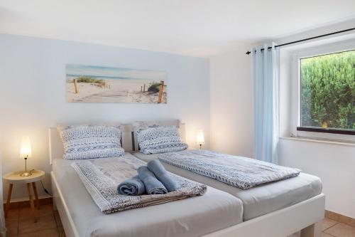a white bedroom with a bed with a window at Ferienanlage Kappeln-Kopperby in Kopperby