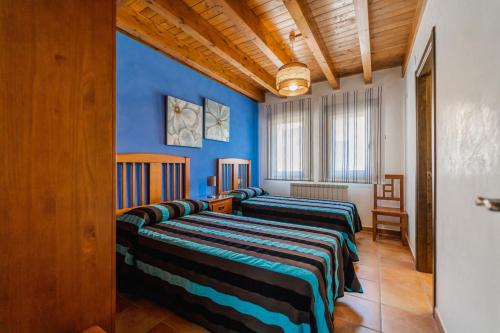 three beds in a room with blue walls at La Dehesa de Santa Ursula in Espeja de San Marcelino