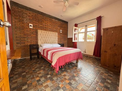 a bedroom with a bed and a brick wall at Casa Bella Vizcaína in Mineral de Pozos