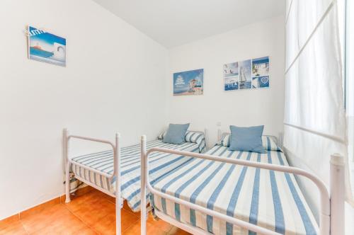 two beds in a room with white walls at White Sands 306 in Arenal d'en Castell