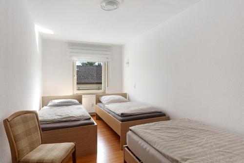 two beds in a room with a chair and a window at Fewo Schneider Bad Wildungen in Bad Wildungen
