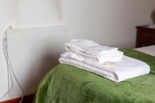 a pile of towels sitting on top of a bed at Casa Da Calçada - Turismo Sortelha in Sortelha