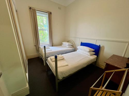 two beds in a small room with a window at Empire Hotel Goulburn in Goulburn