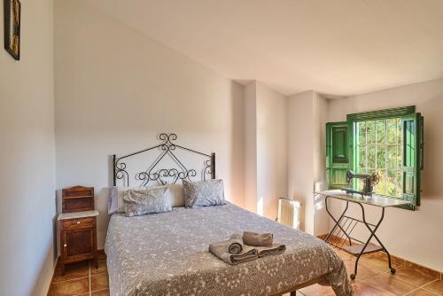 a bedroom with a bed and a window and a table at Casa Ginés in Iznájar