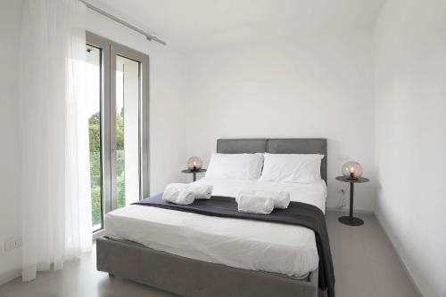 a white bedroom with a large bed with white sheets at Baseventuno 3 bilocale piano terra in Sirmione
