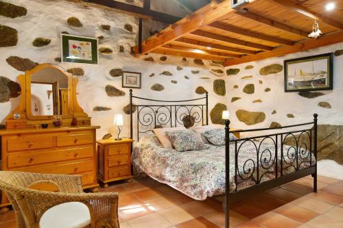 a bedroom with a bed and a dresser and a mirror at Casa Los Pinos in Agüimes