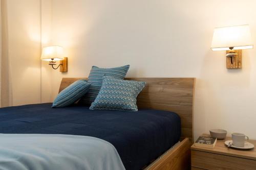 a bedroom with a bed with blue sheets and two lamps at Casa Le Rocce San Pantaleo in San Pantaleo