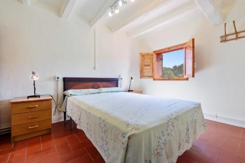 a bedroom with a bed and a dresser and a window at Masia Caltiku in Els Ranxos de Bonany
