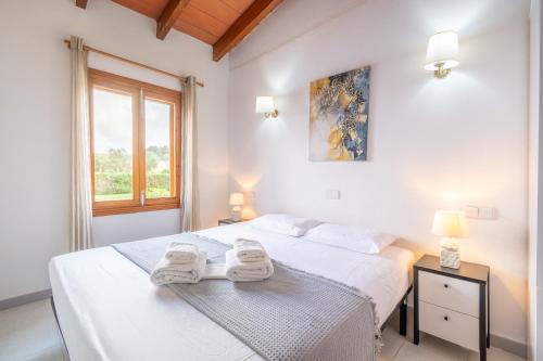 a white bedroom with a bed with towels on it at Can Jaume Des Carritxó in Felanitx