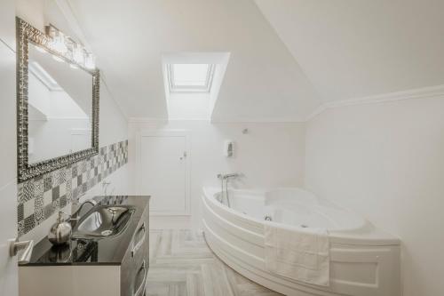 a white bathroom with a tub and a sink at Torres 1 in Quintana de Valdivielso