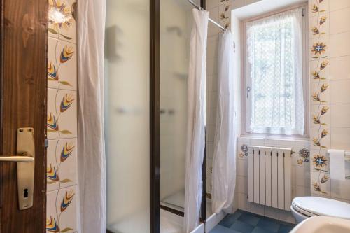 a bathroom with a shower and a toilet and a window at Casa Vacanza Zambotti in Vermiglio