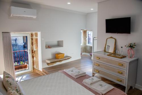 a bedroom with a bed and a dresser with a television at Villa Jerusalém - Casa de Campo in Romeu
