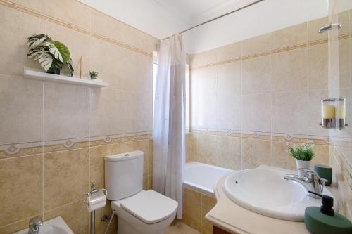 a bathroom with a toilet and a sink and a tub at J R Dream house in Quarteira