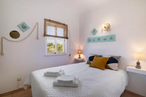 a bedroom with a white bed with towels on it at J R Dream house in Quarteira
