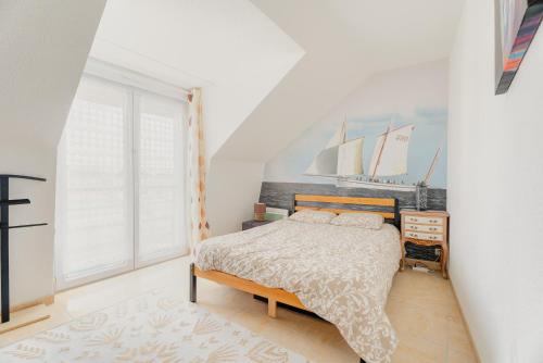 a bedroom with a bed and a window with sailboats on the wall at Le Saint Martin Duplexe à la Mer in Bréhal