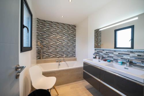 a bathroom with a tub and a sink and a chair at Eden Balinais in Le Muy