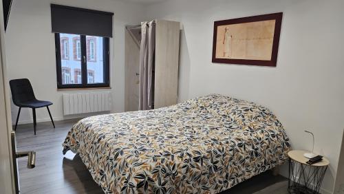 a bedroom with a bed and a chair and a window at gite in Saint-Vaast-la-Hougue