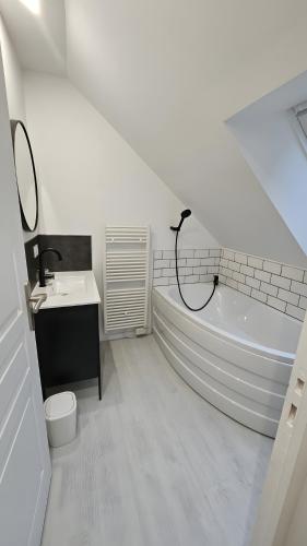 a white bathroom with a tub and a sink at gite in Saint-Vaast-la-Hougue