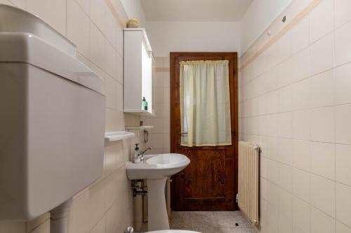a bathroom with a sink and a toilet and a door at Appartamento Al Sasso Rosso Dimaro in Dimaro
