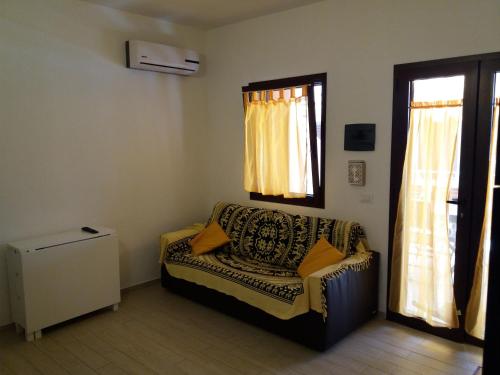 a living room with a couch and two windows at Casa vacanza La Rosa dei Venti in Viddalba