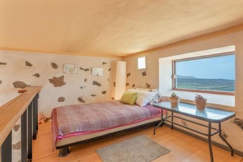 a bedroom with a bed and a table and a window at Finca El Tablero in Tinajo