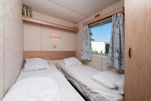 two beds in a small room with a window at Mobilhome kervoyal 56 in Damgan