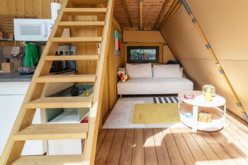 a tiny house with a staircase and a couch at Tipi Lodge Glamp Marguerite in Le Boulou