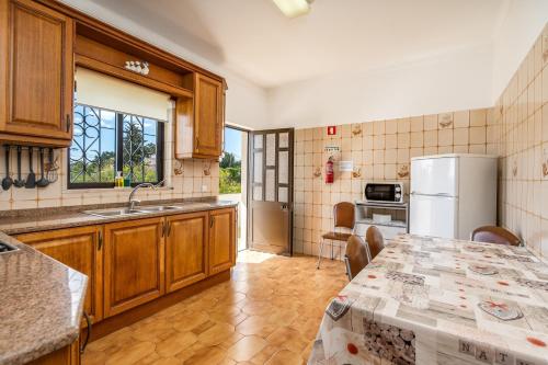 a kitchen with a table and a refrigerator at Vivenda Estrela do Mar in Carvoeiro