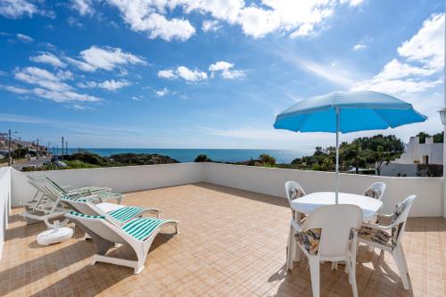 a patio with a table and chairs and an umbrella at Vivenda Estrela do Mar in Carvoeiro