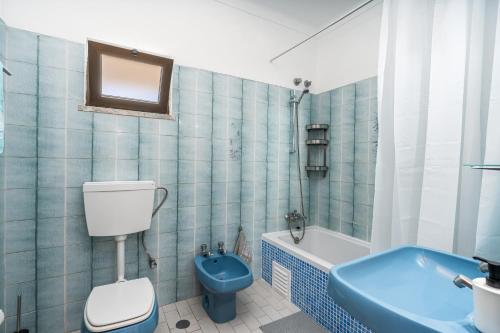 a bathroom with a blue toilet and a tub at Vivenda Estrela do Mar in Carvoeiro